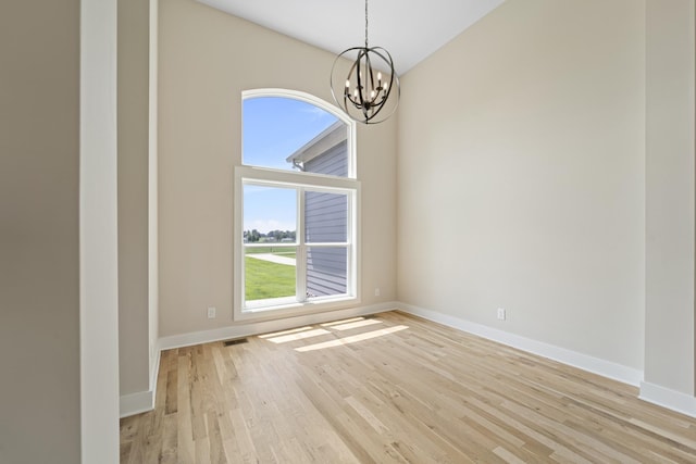 unfurnished room featuring light hardwood / wood-style flooring and a notable chandelier