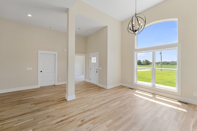 interior space featuring high vaulted ceiling, an inviting chandelier, and light hardwood / wood-style floors