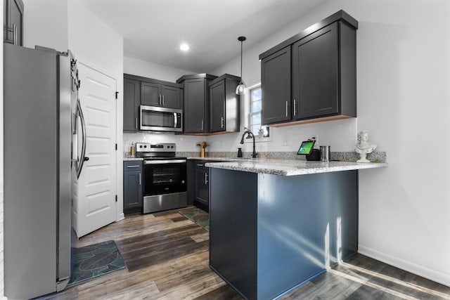 kitchen featuring light stone countertops, decorative light fixtures, dark wood-type flooring, stainless steel appliances, and decorative backsplash