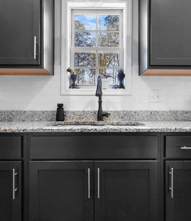 room details with sink, light stone countertops, and tasteful backsplash