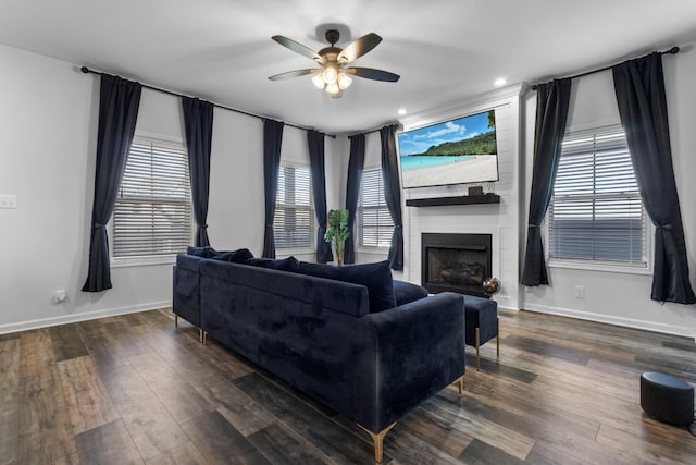 living room with ceiling fan, a healthy amount of sunlight, dark hardwood / wood-style floors, and a fireplace