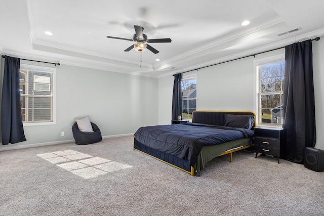 carpeted bedroom featuring ceiling fan, multiple windows, a tray ceiling, and crown molding