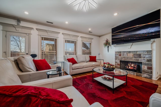 living room featuring hardwood / wood-style flooring, a healthy amount of sunlight, crown molding, and a fireplace