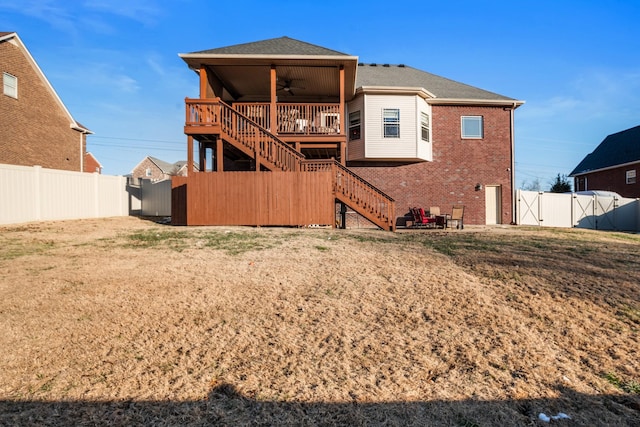 back of house featuring ceiling fan, a deck, and a lawn