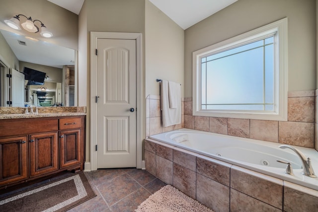 bathroom featuring vaulted ceiling, tiled tub, and vanity