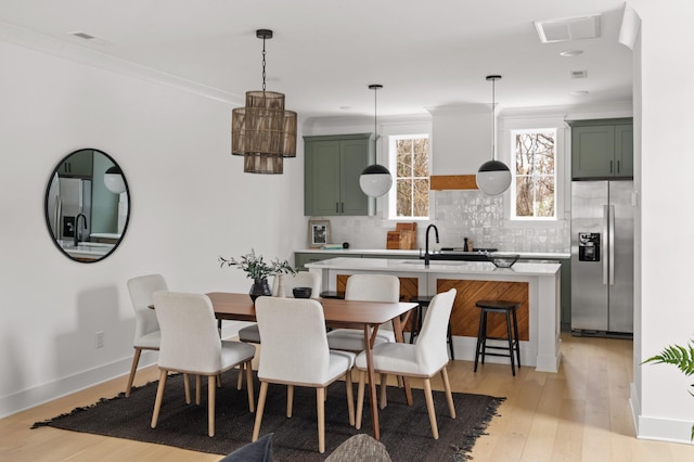 dining room with crown molding, sink, and light hardwood / wood-style flooring