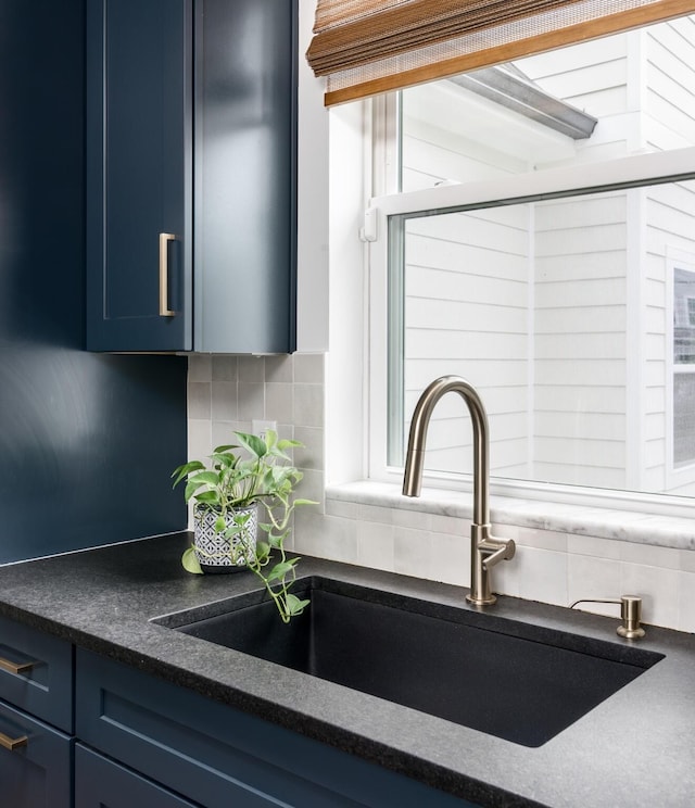 room details featuring sink, blue cabinets, and decorative backsplash