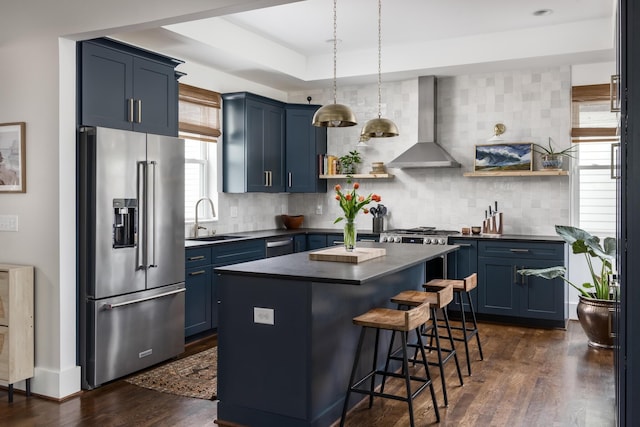 kitchen with high quality fridge, wall chimney range hood, and blue cabinets