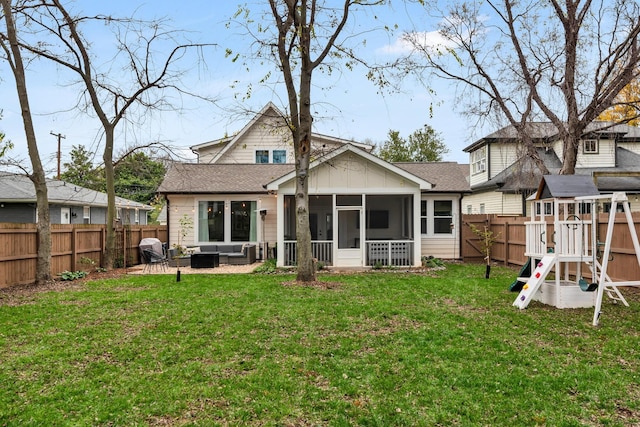 rear view of property featuring a playground, a sunroom, a lawn, a patio area, and an outdoor hangout area