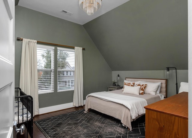 bedroom featuring dark wood-type flooring, a notable chandelier, and vaulted ceiling