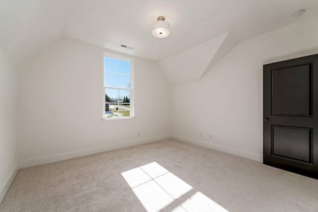 bonus room with light carpet and vaulted ceiling