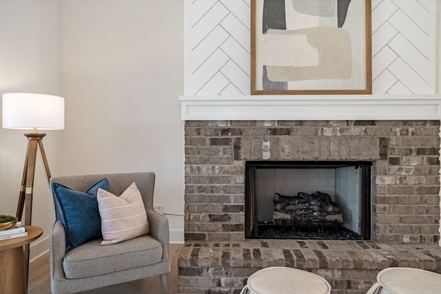 living area featuring hardwood / wood-style flooring and a brick fireplace