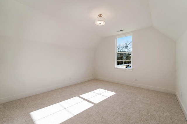 additional living space featuring vaulted ceiling and light carpet