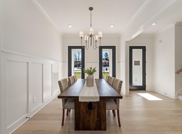 dining space with an inviting chandelier, light wood-type flooring, and ornamental molding