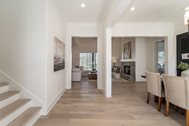 entryway with crown molding, light wood-type flooring, and a fireplace