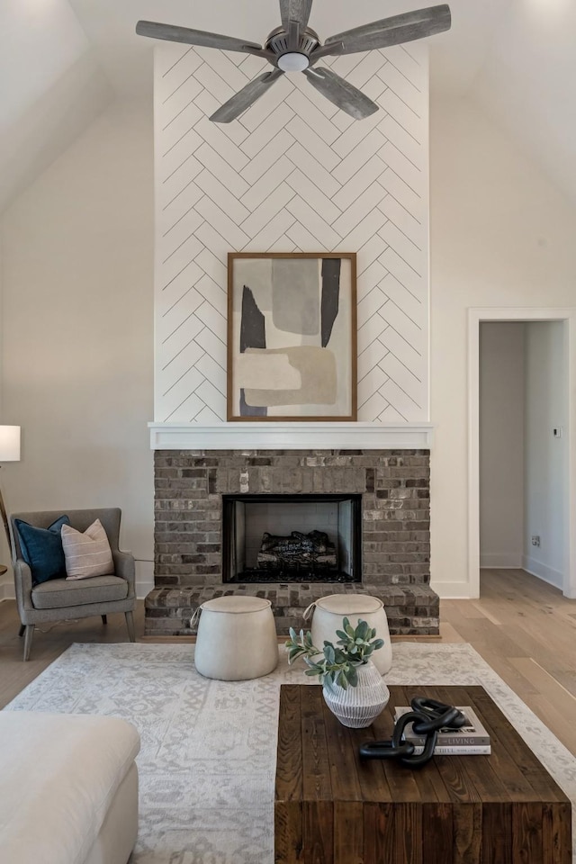 living room featuring vaulted ceiling, ceiling fan, light hardwood / wood-style floors, and a fireplace