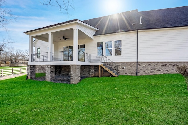 back of house with ceiling fan and a lawn