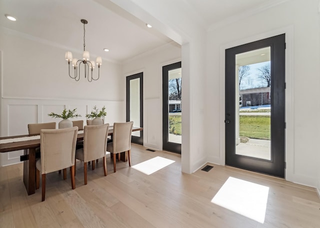 dining area featuring a wealth of natural light, ornamental molding, and an inviting chandelier