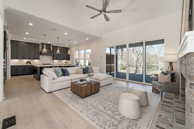 living room with ceiling fan, light hardwood / wood-style floors, a fireplace, and lofted ceiling