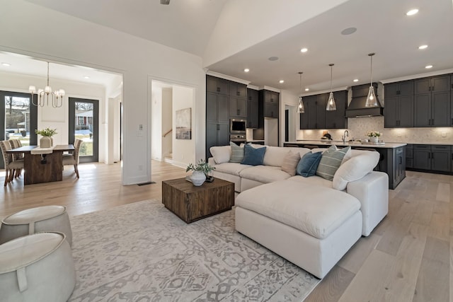 living room with light hardwood / wood-style floors, an inviting chandelier, and vaulted ceiling