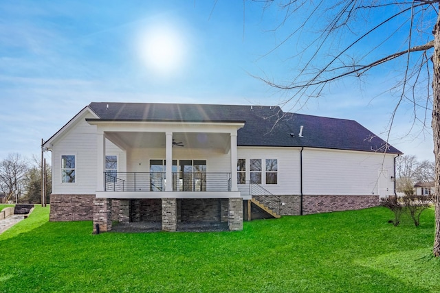 back of house with ceiling fan, a balcony, and a lawn