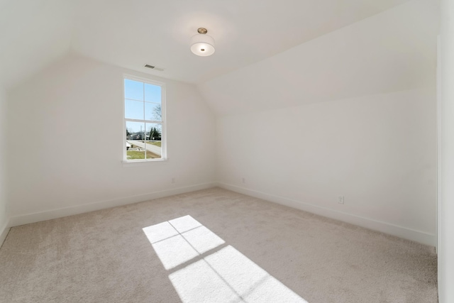 additional living space featuring vaulted ceiling and light colored carpet