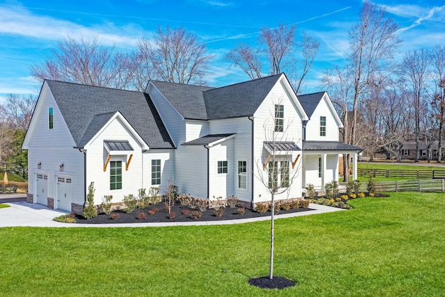 modern inspired farmhouse with covered porch, a garage, and a front lawn