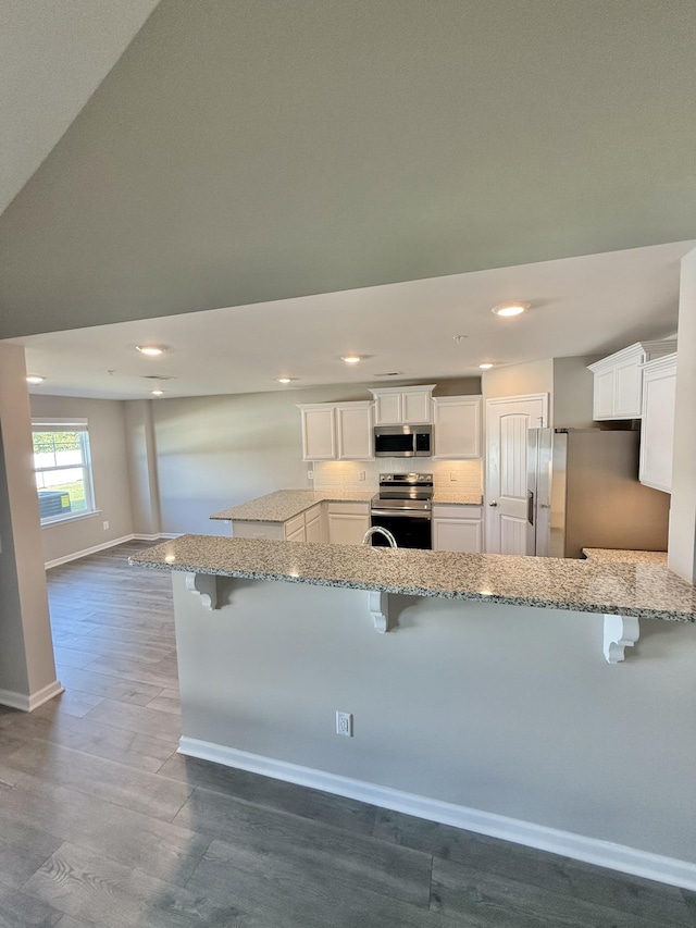 kitchen with kitchen peninsula, a kitchen bar, and appliances with stainless steel finishes