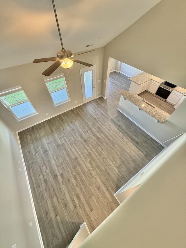 unfurnished living room with ceiling fan, light hardwood / wood-style floors, and lofted ceiling