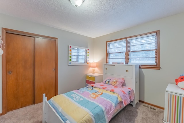 carpeted bedroom with a textured ceiling and a closet