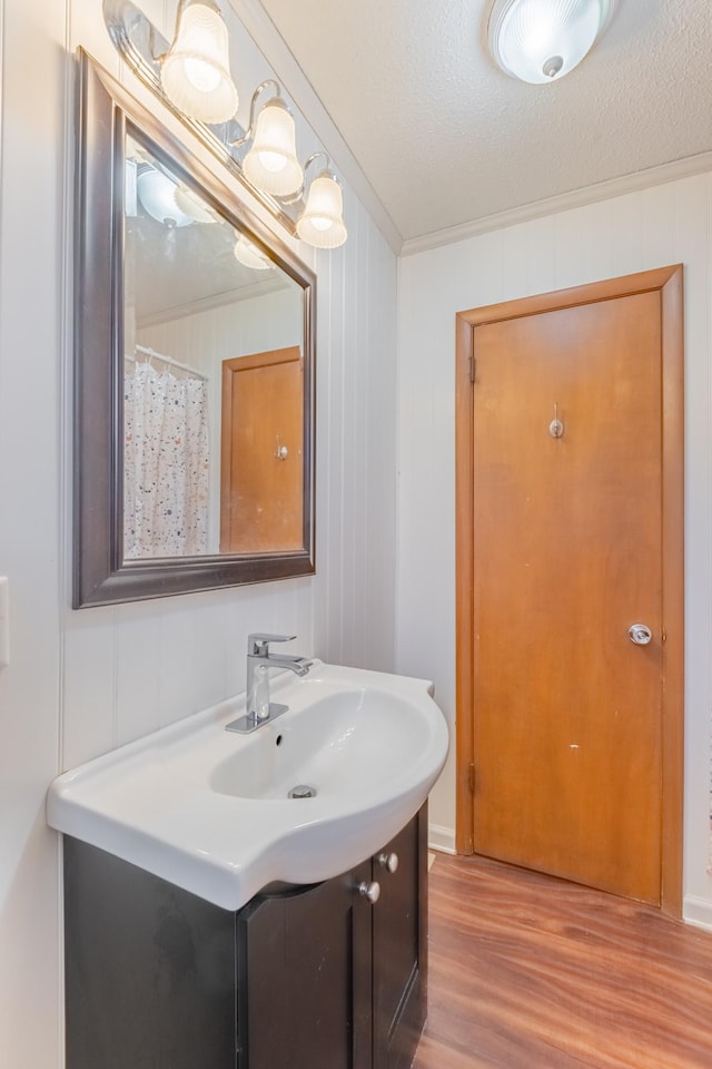 bathroom with vanity, hardwood / wood-style floors, ornamental molding, and a textured ceiling