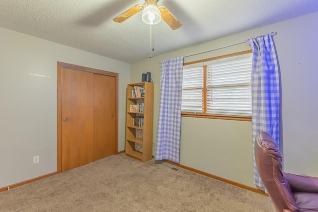 unfurnished bedroom with light carpet, a textured ceiling, a closet, and ceiling fan