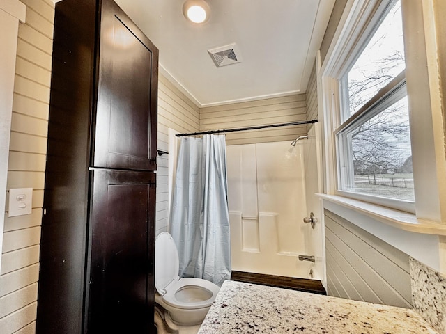 bathroom with wood walls, toilet, and shower / bath combo with shower curtain