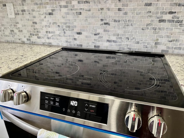 interior details with tasteful backsplash, light stone countertops, and electric range