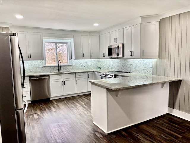 kitchen featuring white cabinetry, kitchen peninsula, sink, light stone counters, and appliances with stainless steel finishes