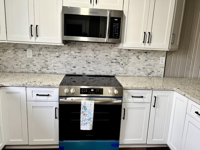 kitchen featuring white cabinets, appliances with stainless steel finishes, light stone countertops, and decorative backsplash