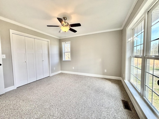 unfurnished bedroom with carpet flooring, a closet, crown molding, and ceiling fan