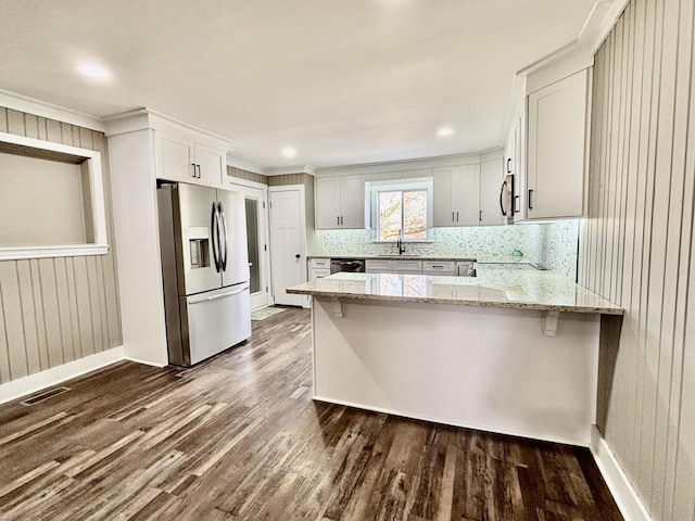 kitchen featuring appliances with stainless steel finishes, sink, white cabinetry, kitchen peninsula, and light stone countertops