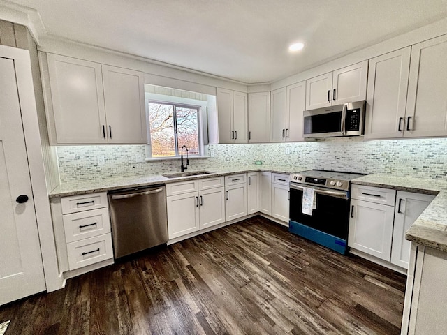 kitchen featuring appliances with stainless steel finishes, dark wood-type flooring, light stone countertops, sink, and white cabinetry