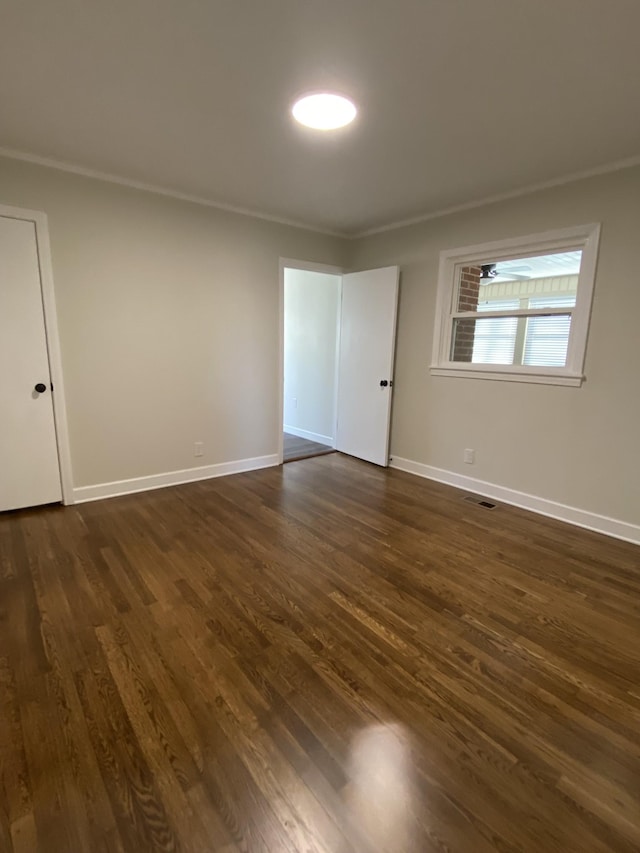 unfurnished room with dark hardwood / wood-style flooring and ornamental molding