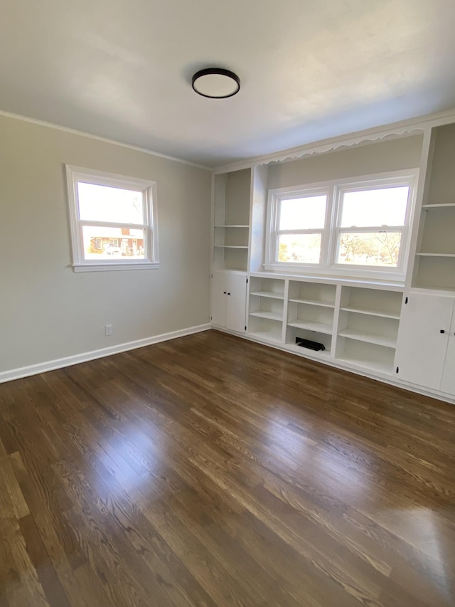 unfurnished room featuring built in features, a healthy amount of sunlight, and dark hardwood / wood-style flooring