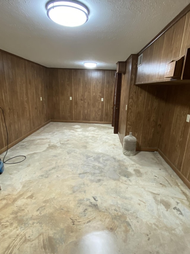 basement featuring a textured ceiling and wood walls