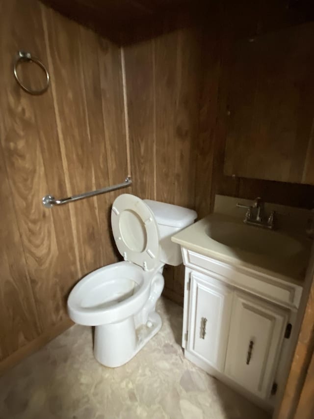 bathroom featuring vanity, toilet, and wooden walls