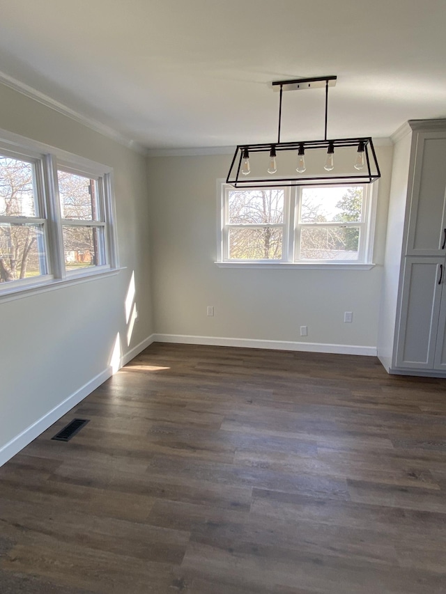 spare room with dark wood-type flooring, track lighting, and ornamental molding