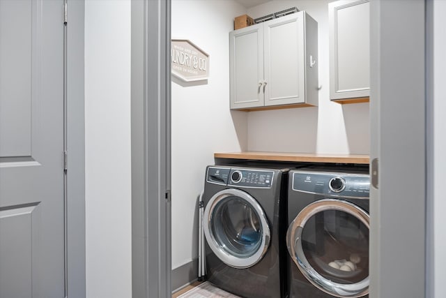 clothes washing area with washer and dryer and cabinets