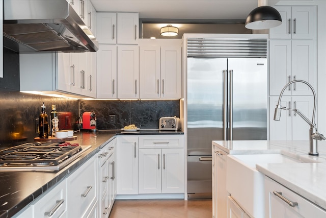 kitchen featuring appliances with stainless steel finishes, sink, tasteful backsplash, extractor fan, and white cabinetry