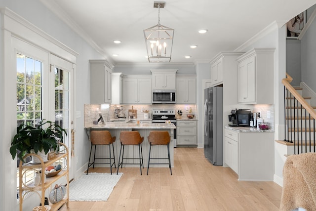 kitchen featuring a kitchen bar, appliances with stainless steel finishes, tasteful backsplash, white cabinetry, and kitchen peninsula