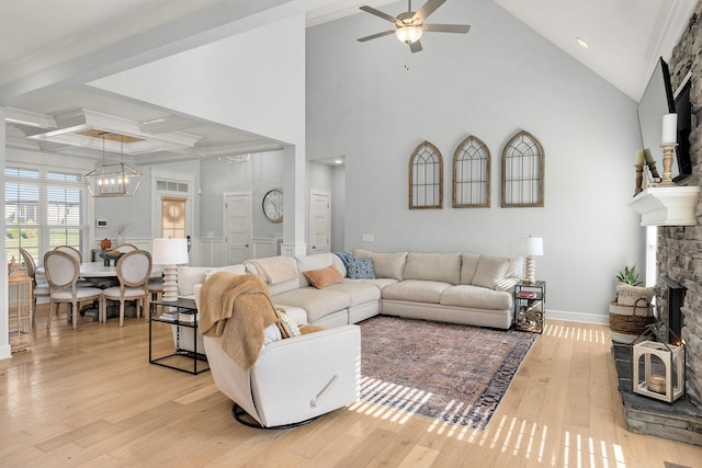 living room featuring beamed ceiling, crown molding, light hardwood / wood-style floors, a fireplace, and ceiling fan with notable chandelier