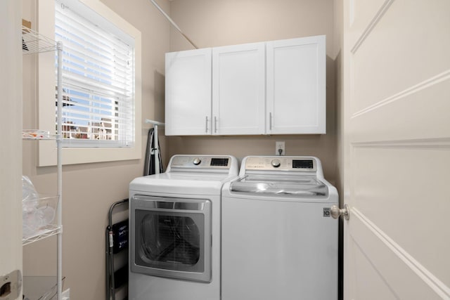 clothes washing area featuring washing machine and dryer and cabinets