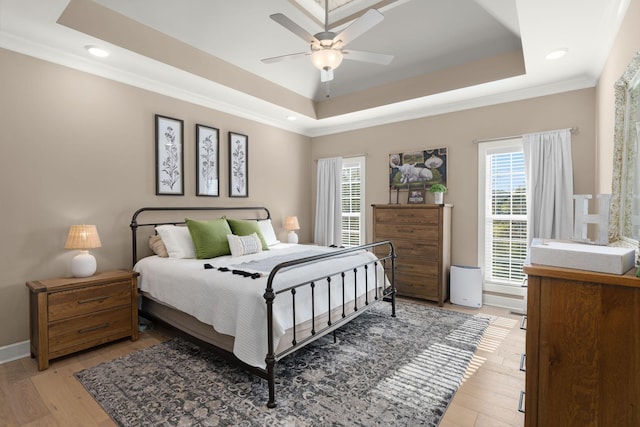 bedroom featuring ceiling fan, light hardwood / wood-style flooring, a raised ceiling, and ornamental molding